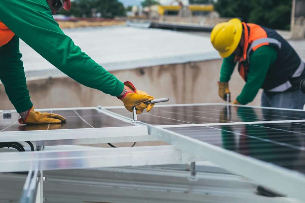 Workers secure solar panels on a rooftop, advancing renewable energy.