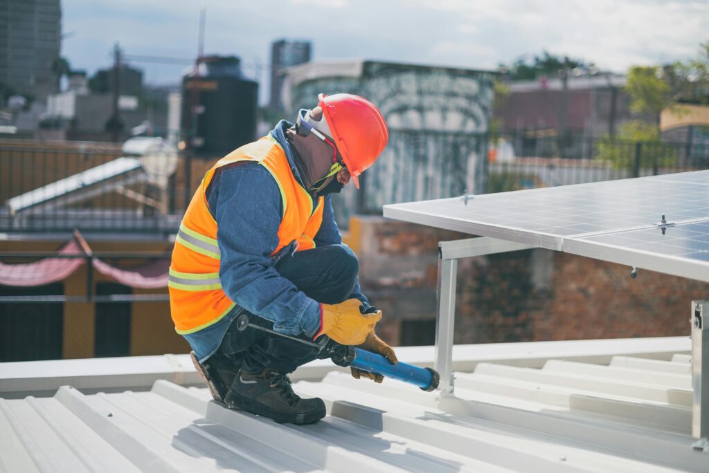 Technician in safety gear installing solar panels on a rooftop, ensuring energy efficiency.