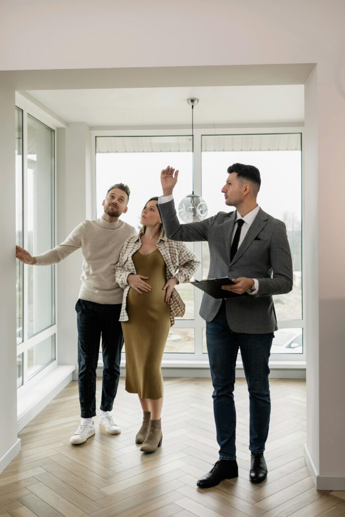 A couple tours a modern home with a real estate agent, exploring their potential new living space.