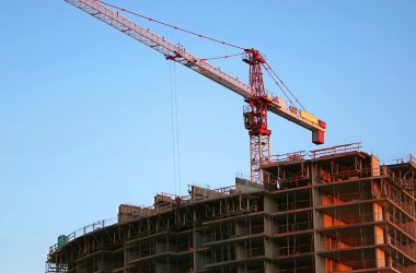 Tower crane on a high-rise building under construction at sunset, showcasing modern urban development.